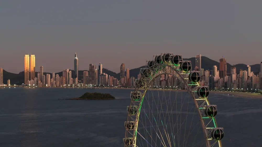 Roda-gigante e edifícios da orla de Balneário Camboriú ao entardecer